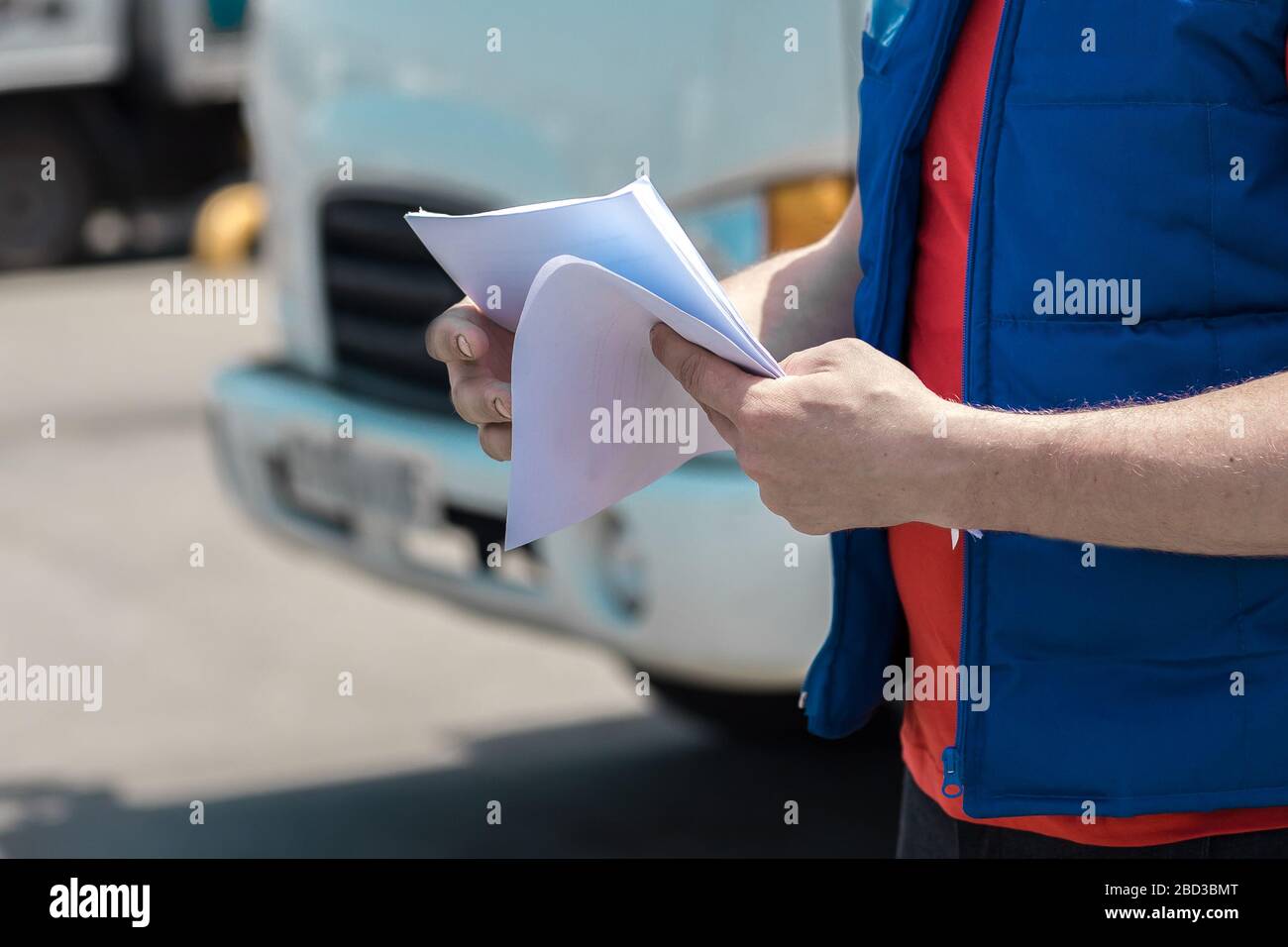 Corriere in uniforme prendendo appunti nel documento e consegna camion bianco lo behinde Foto Stock