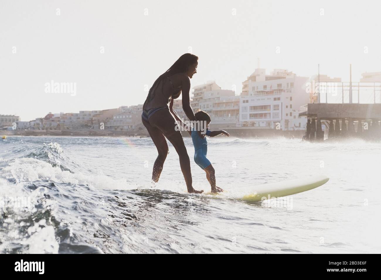 Vista completa di madre e figlio che naviga in una piccola onda sul mare Foto Stock