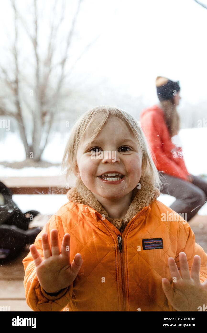 occhi larghi sorridendo 3 anni la ragazza guarda attraverso finestra pannello a zio Foto Stock