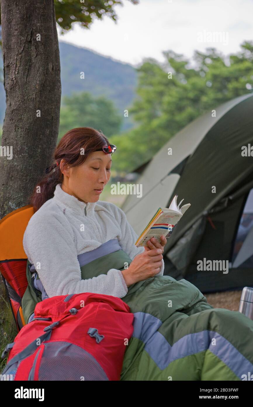 donna che legge un libro al campeggio Foto Stock