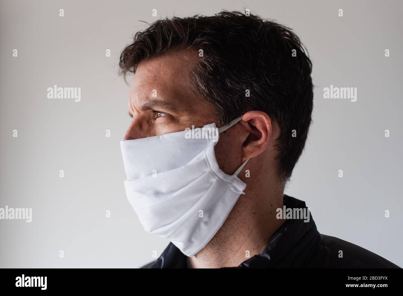 Uomo che indossa la maschera faccia in tessuto fatta in casa durante Covid 19 pandemic. Foto Stock