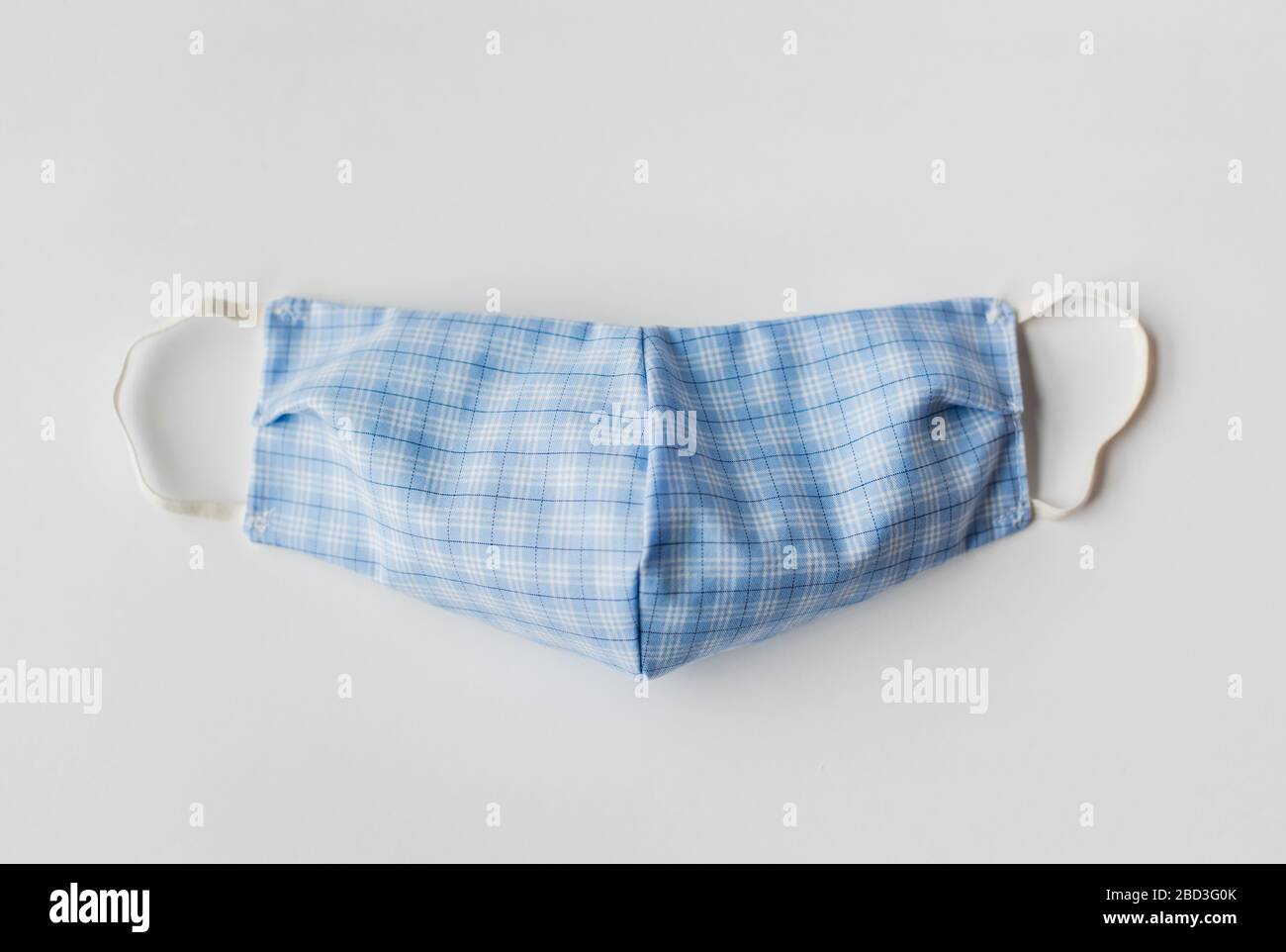 Maschera facciale in tessuto fatta in casa utilizzata durante Covid-19 su sfondo bianco. Foto Stock