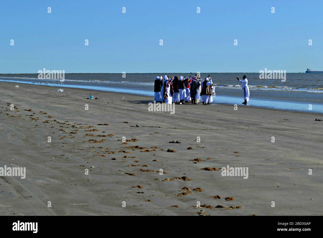 Le donne nere e un prete stanno pregando sulla spiaggia di Galveston, Texas Foto Stock