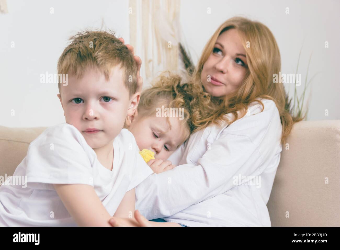 La ragazza si addormentò tra le braccia della madre. Un ragazzo serio guarda nella fotocamera. Foto Stock