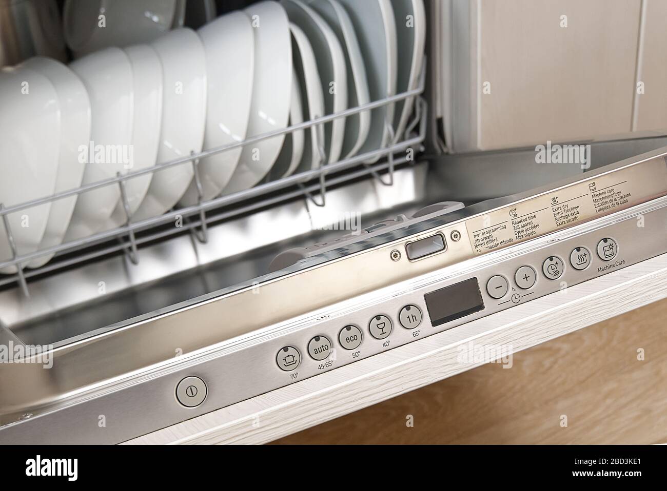 Lavastoviglie a pieno carico. Lavastoviglie integrata con piastre bianche davanti a vista Foto Stock