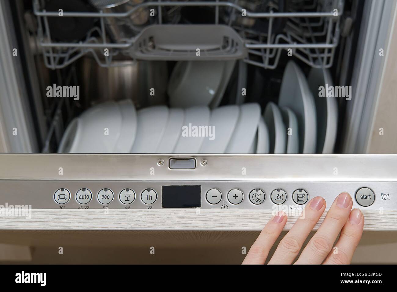Lavastoviglie a pieno carico. Lavastoviglie integrata con piastre bianche davanti a vista Foto Stock