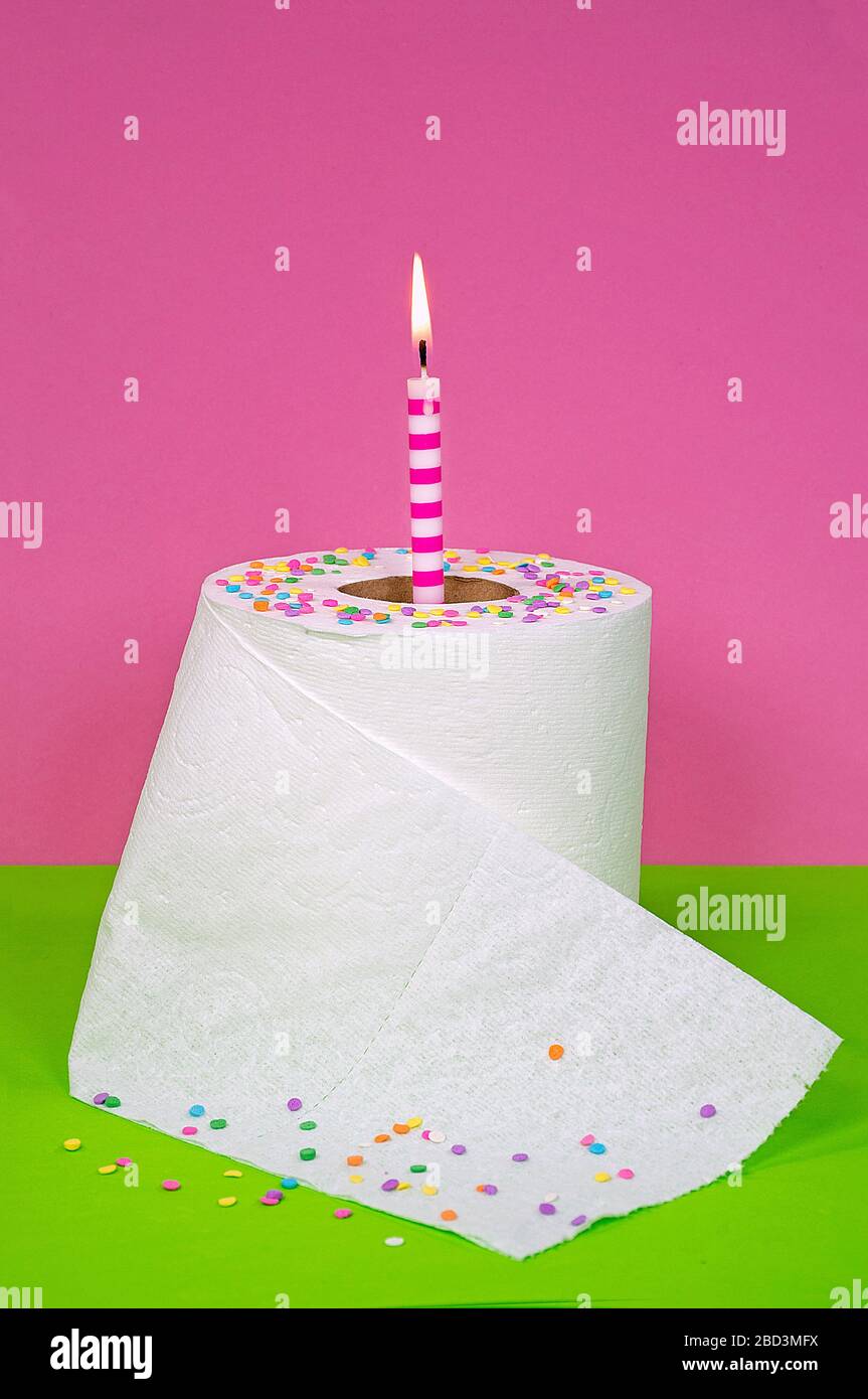 confetti caramella e candela di compleanno in rotolo di carta igienica bianca su sfondo verde e rosa Foto Stock