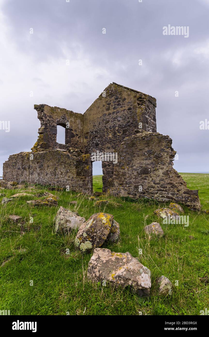 Prospettiva bassa di rovine del patrimonio su un cavoll erboso a Stanley, Tasmania in una giornata di overcast. Foto Stock