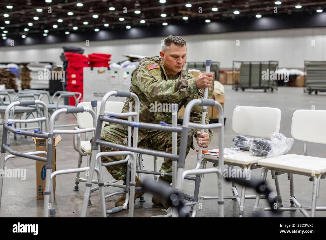 Detroit, Michigan, Stati Uniti. 6 Aprile 2020. I lavoratori costruiscono un ospedale di emergenza presso il centro congressi TCF. L'ospedale a 1,000 letti si occuperà dei pazienti con Covid-19. Un membro della Guardia Nazionale del Michigan assembla gli escursionisti. Credit: Jim West/Alamy Live News Foto Stock