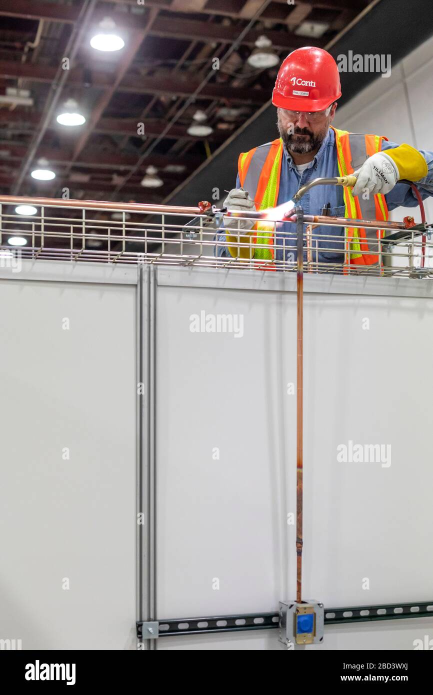 Detroit, Michigan, Stati Uniti. 6 Aprile 2020. I lavoratori costruiscono un ospedale di emergenza presso il centro congressi TCF. L'ospedale a 1,000 letti si occuperà dei pazienti con Covid-19. Un'unità di tubazioni installa una tubazione di alimentazione dell'ossigeno. Credit: Jim West/Alamy Live News Foto Stock