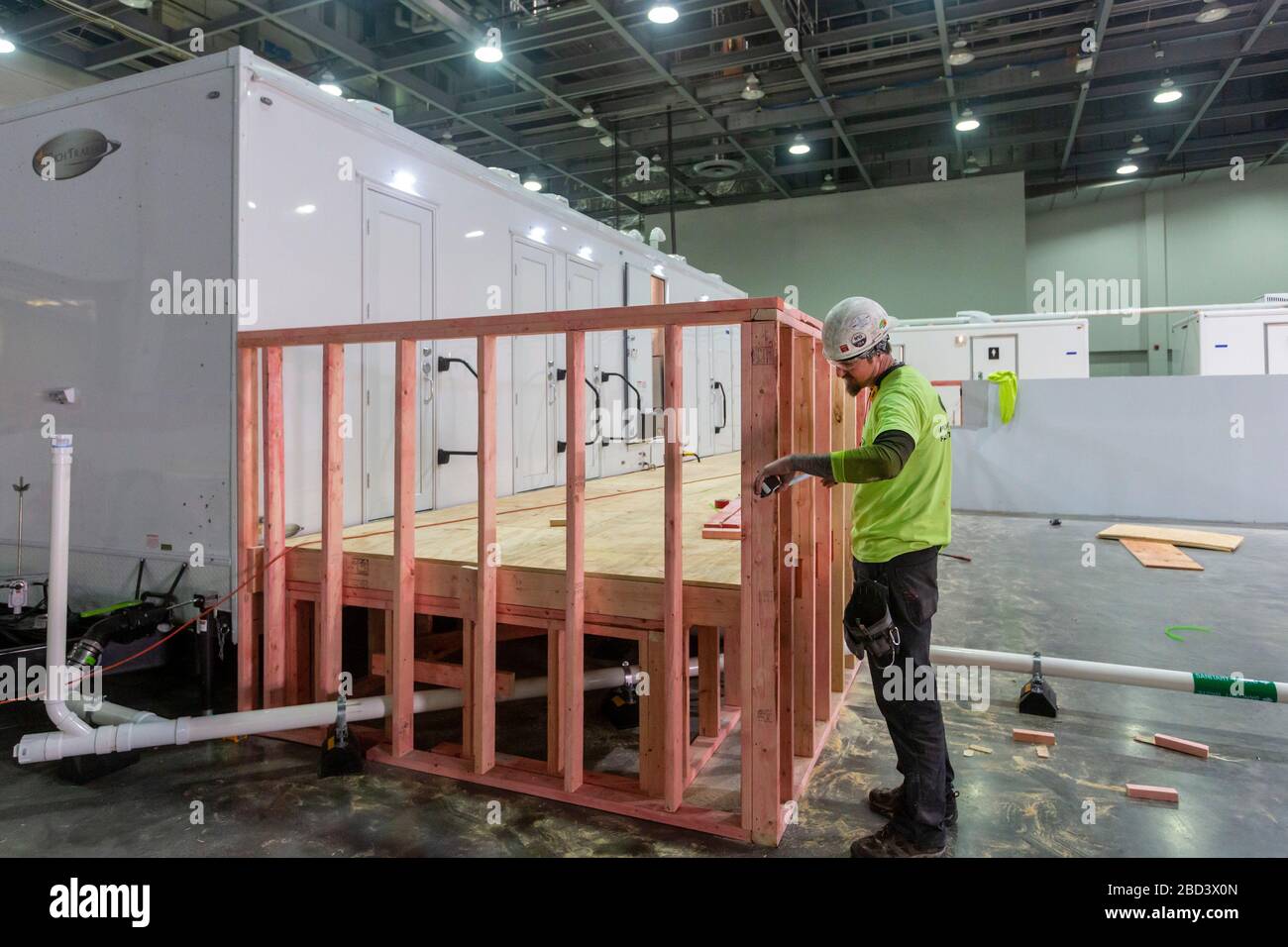 Detroit, Michigan, Stati Uniti. 6 Aprile 2020. I lavoratori costruiscono un ospedale di emergenza presso il centro congressi TCF. L'ospedale a 1,000 letti si occuperà dei pazienti con Covid-19. Un falegname lavora su una cabina doccia. Credit: Jim West/Alamy Live News Foto Stock