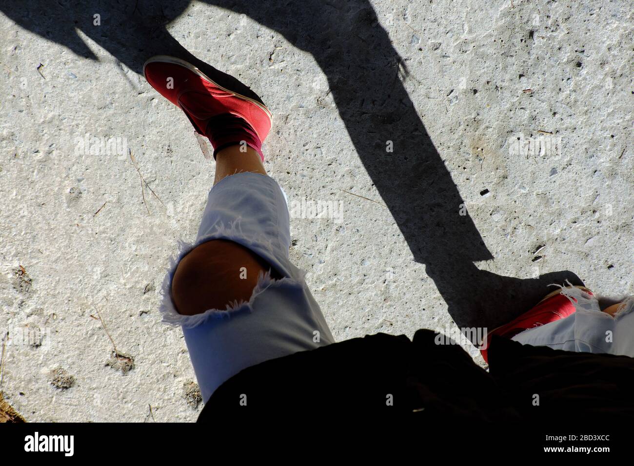 Vista spettacolare quando la fotografa femminile si fa il selfie al mattino presto, ombra divertente da Jean strappato al ginocchio e scarpe rosse da persone in piedi Foto Stock