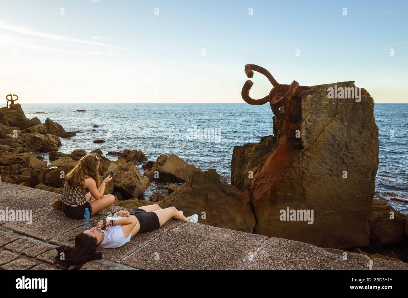 San Sebastian, Gipuzkoa, Paesi Baschi, Spagna : i visitatori siedono accanto al pettine del vento (Peine del viento/Haizearen orrazia) scultura Foto Stock