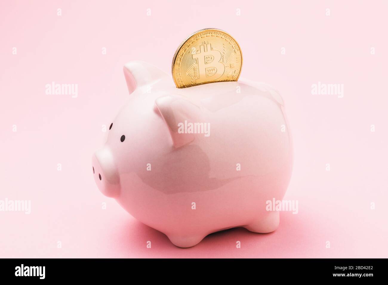 Bitcoin in una banca piggy su uno sfondo rosa. Concetto sul tema della conservazione della moneta in valuta digitale Foto Stock