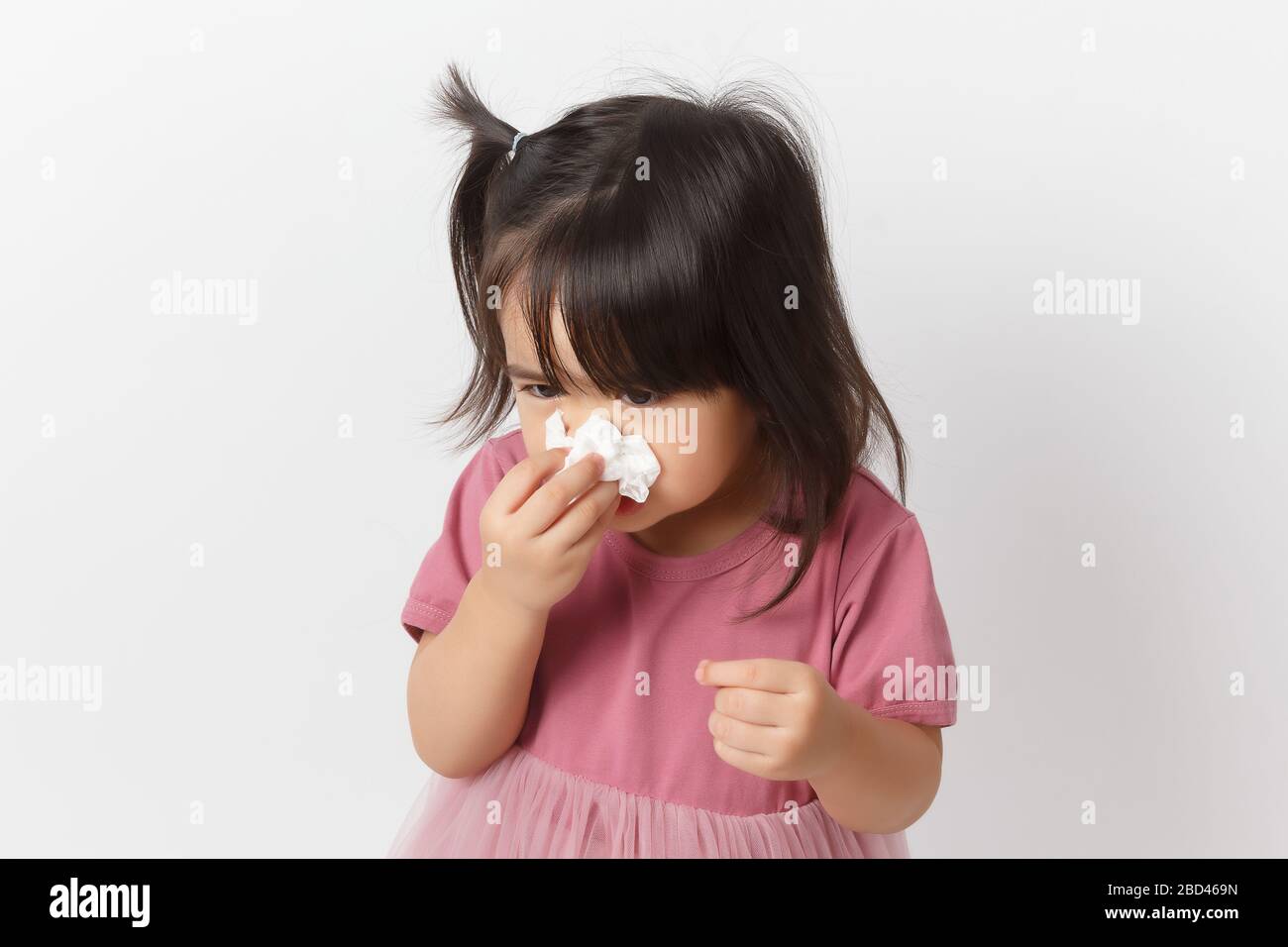 Piccola ragazza asiatica che tiene un tessuto e soffiare il naso. Capretto con rinite fredda. Virus e infezione. Sintomo di coronavirus Foto Stock