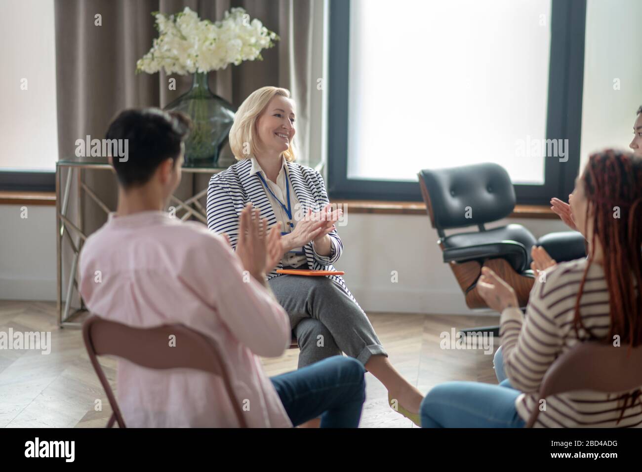 Psicologo biondo in una giacca grigia che guarda compiaciuto Foto Stock