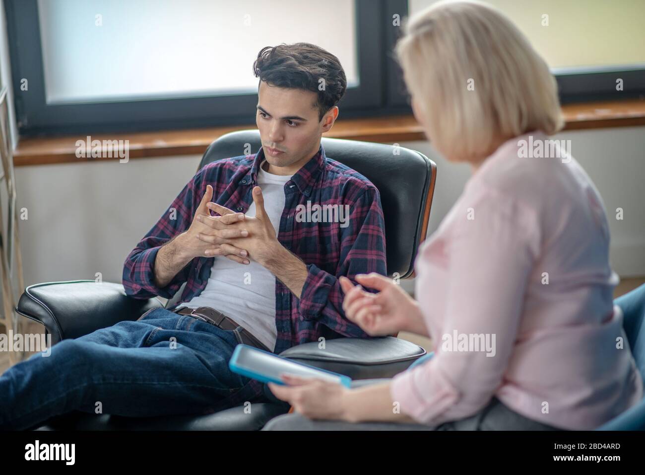 Giovane uomo che ha una sessione di terapia e che guarda turbato Foto Stock