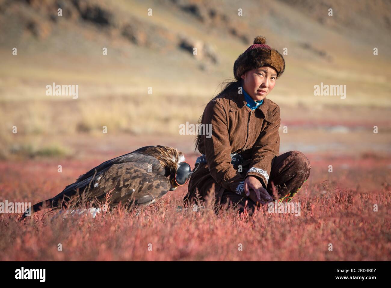 Tradizionale giovane cacciatrice di aquila kazaka con la sua aquila dorata che è usata per la caccia di volpe e pelliccia di coniglio. Ulgii, Mongolia occidentale. Foto Stock