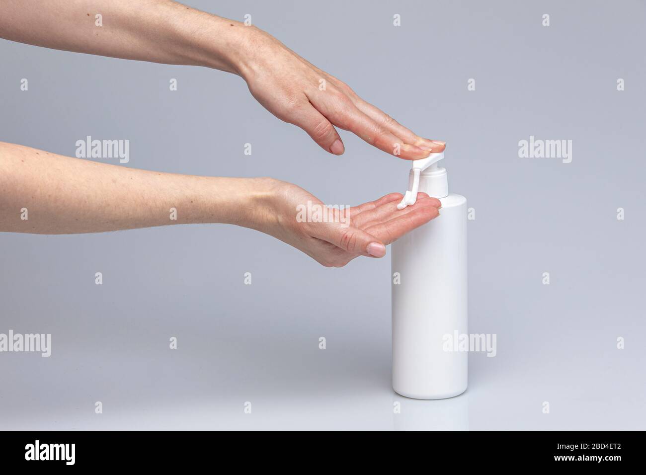 Le mani bianche si lavano con il sapone verde schiumoso di Marsiglia isolato di fronte a uno sfondo grigio con luci e ombre strutturanti Foto Stock