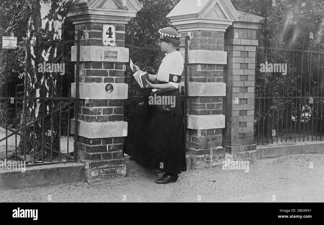 Donna portatrice di posta presso un cancello di una casa, a Berlino, Germania durante la guerra mondiale i ca. 1910-1915 Foto Stock