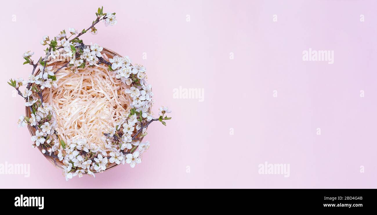 Cesto vuoto con una corona di fiori bianchi su sfondo rosa. Posizionare per il testo Flatley. Vista dall'alto. Oggetto sul lato sinistro della foto Foto Stock