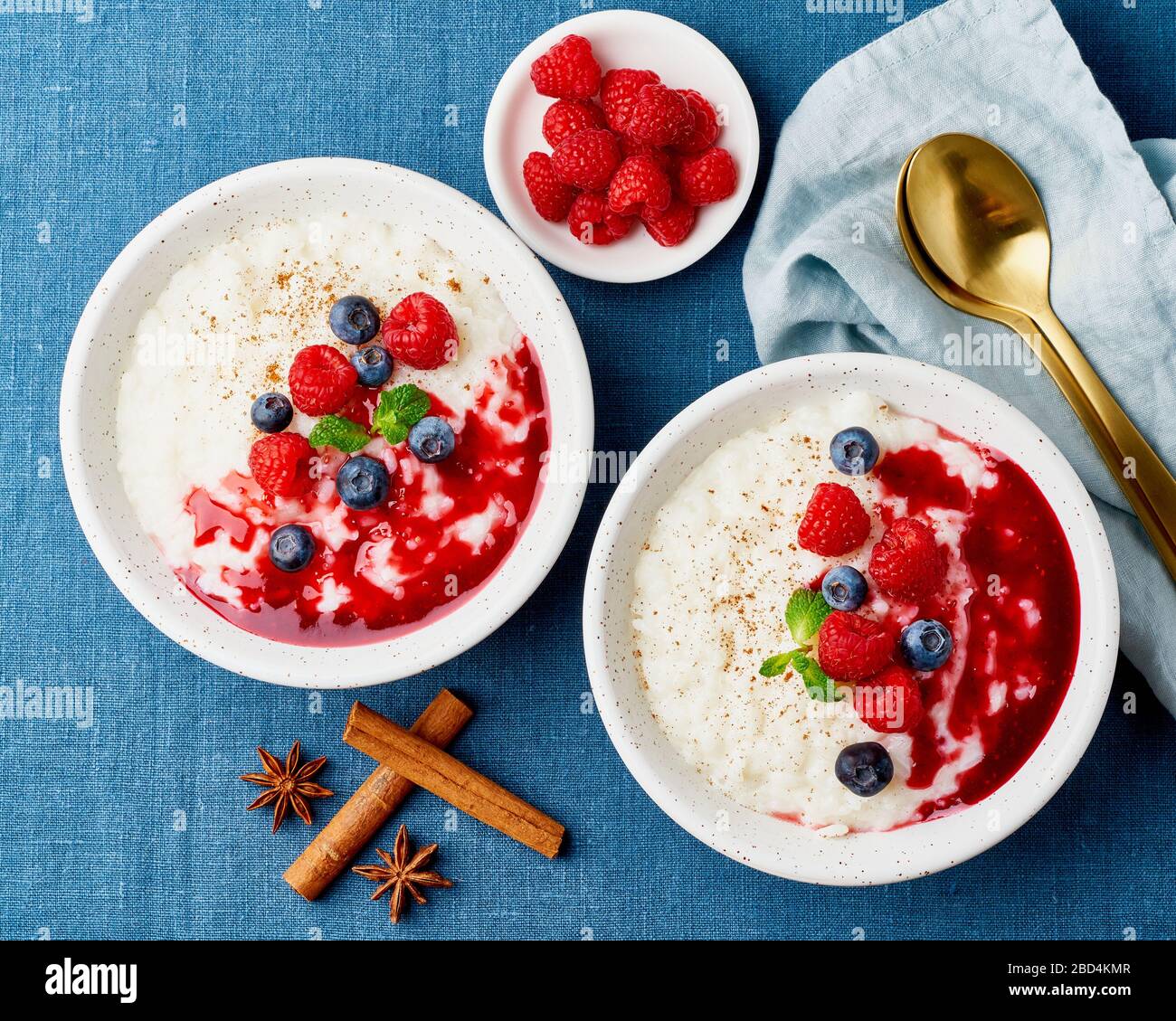 Budino di riso. Dessert francese di riso al latte con lamponi e mirtilli. Tessuto di lino blu. Vista dall'alto Foto Stock
