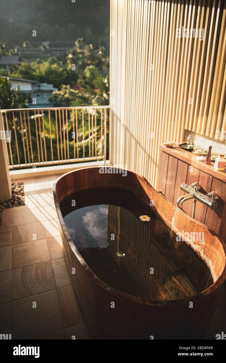 Vasca da bagno in legno marrone piena di acqua sul balcone con vista pittoresca sulle verdeggianti palme jungles nel villaggio di Ao Nang nella provincia di Krabi, Thailandia Foto Stock