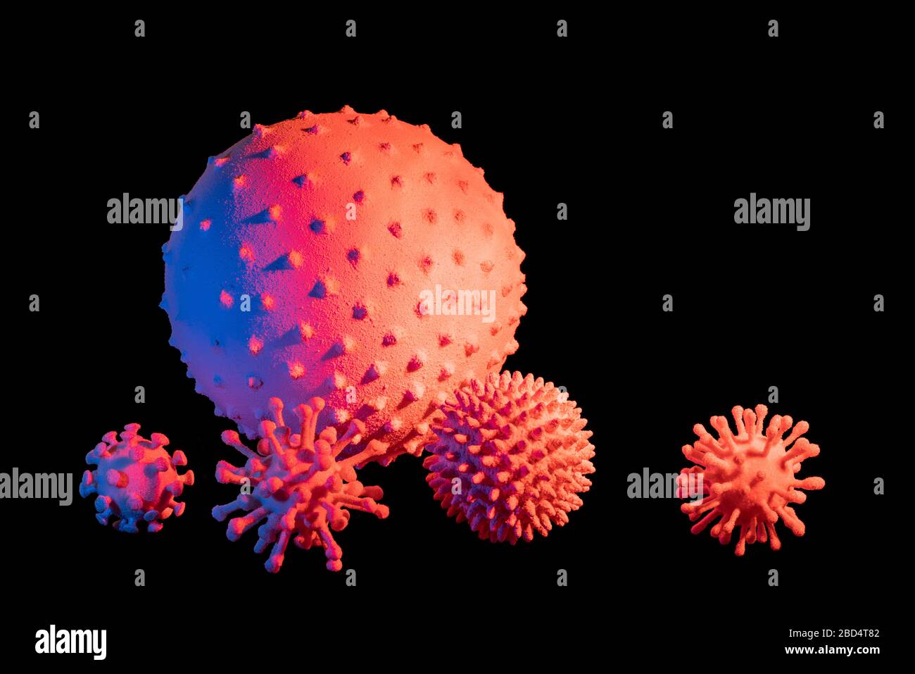 immagine di alcuni colorati virus simbolici illuminati in nero sul retro Foto Stock