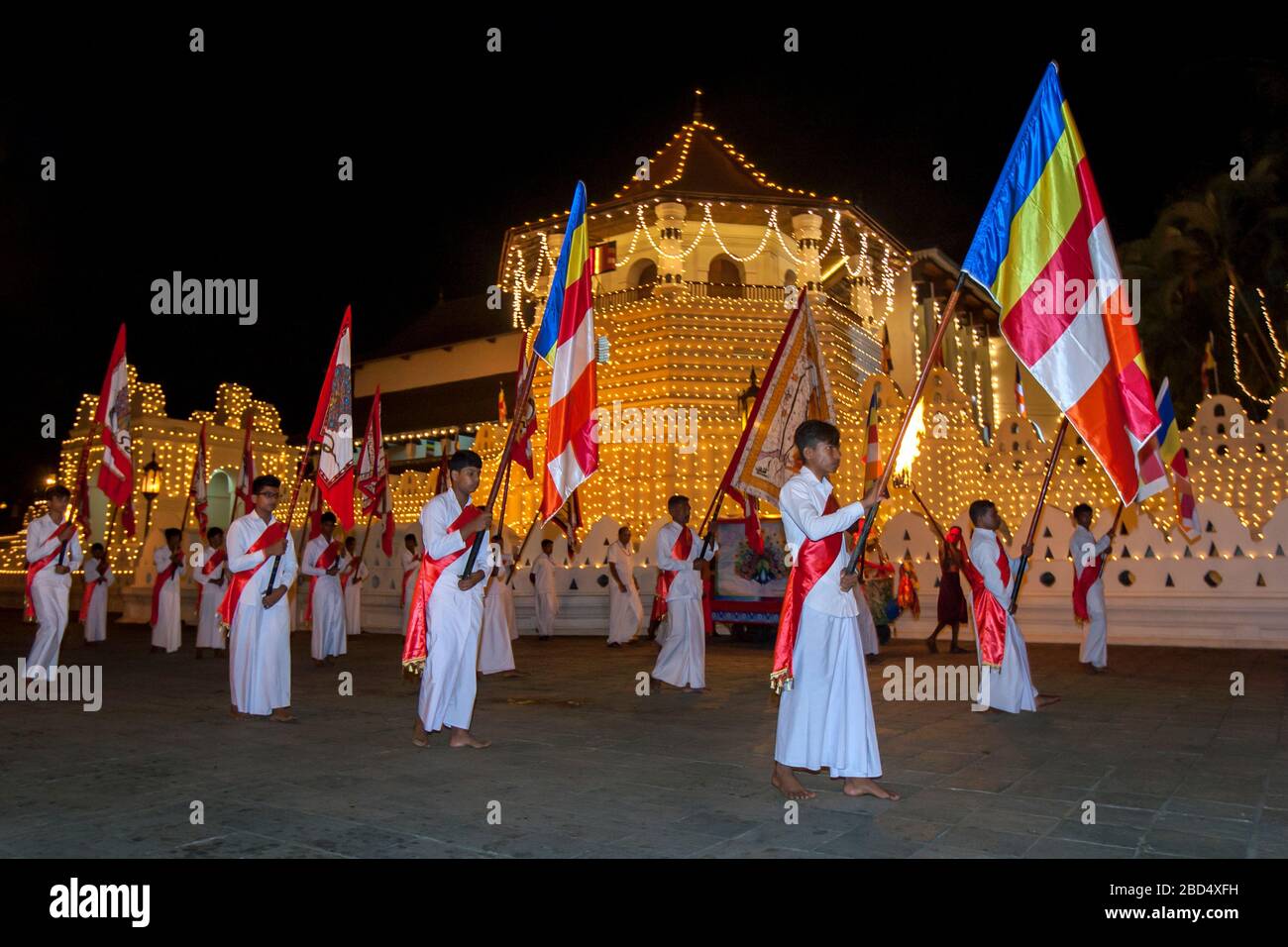 I portieri della bandiera buddista parasano davanti al Tempio della reliquia del dente Sacro durante la Esala Perahera (grande processione) a Kandy in Sri Lanka. Foto Stock