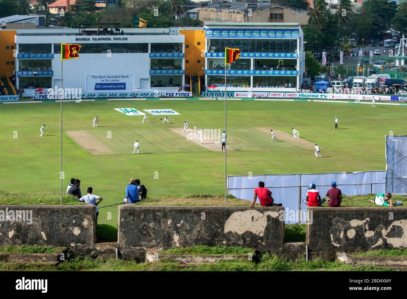 La gente siede su una sezione del Forte Olandese (1588) a Galle in Sri Lanka guardando una partita di cricket al Galle International Cricket Ground. Foto Stock
