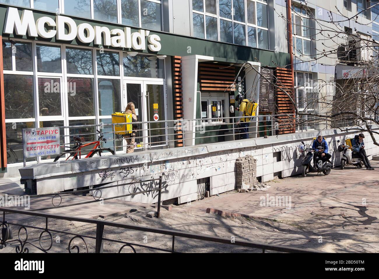 Kiev, Ucraina - 06 aprile 2020: Corrieri e servizi di consegna Glovo in coda vicino al McDonald's. L'Ucraina ferma bar, ristoranti e negozi Foto Stock