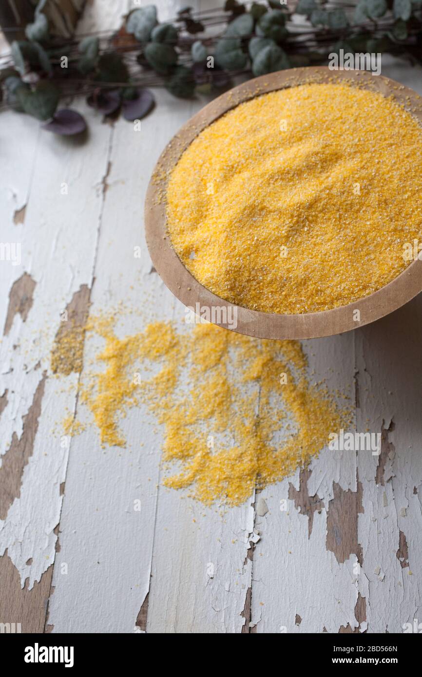 Una ciotola di polenta con i grani che versano su una superficie bianca Foto Stock