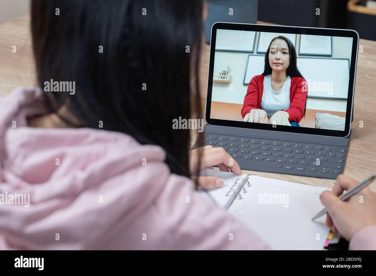 Una donna asiatica che parla mentre chiacchiera video con un collega. Foto Stock