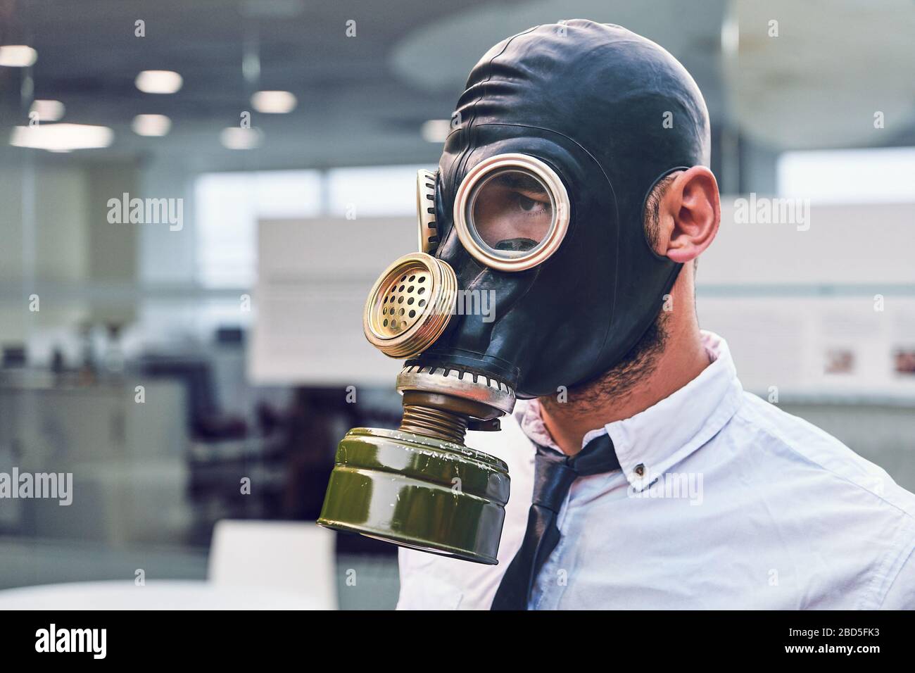 Quarantena del coronavirus. Giovane dipendente in ufficio, al lavoro con maschera a pieno facciale. Protezione dalle infezioni. Foto Stock