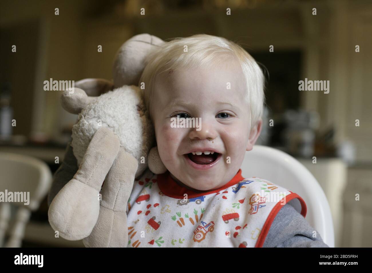 Bambino che ride e gioca con un giocattolo morbido e coccoloso a casa durante il periodo di autoisolamento durante la pandemia del coronavirus 2020 COVID-19 Foto Stock