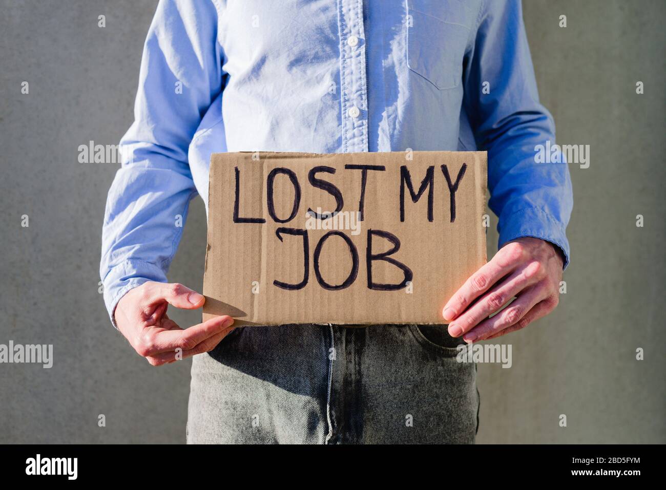 Uomo lavoratore in ufficio in camicia blu con segno di cartone PERSO LAVORO. Senza lavoro, concetto di disoccupazione. Chiedere soldi Foto Stock
