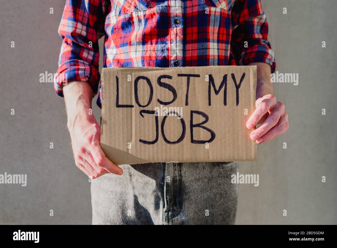 Uomo lavoratore in camicia a plaid con segno di cartone PERSO LAVORO. Senza lavoro, concetto di disoccupazione. Chiedere soldi Foto Stock