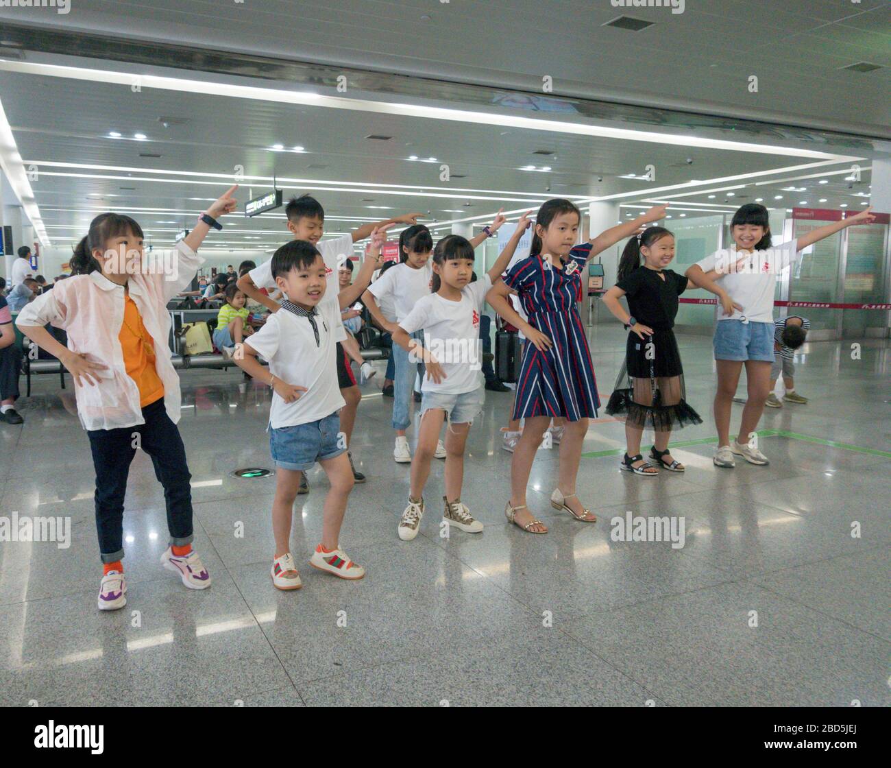 Childen esecuzione di canzoni e danza routine di musica, lounge partenze, aeroporto di Quanzhou, Cina Foto Stock