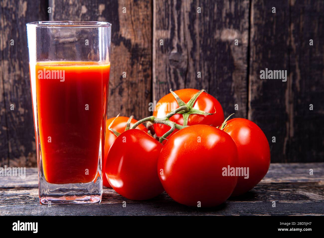 bicchiere di succo di pomodoro e pomodori su sfondo di legno Foto Stock