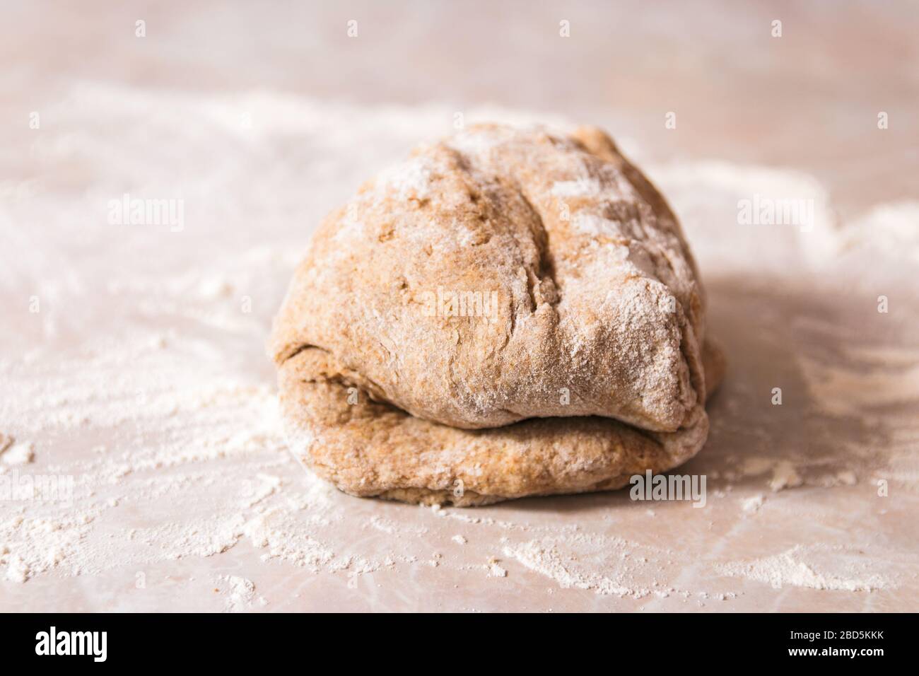 processo di cottura del pane di salute a casa. primo piano donna mani impastare l'impasto da farina di segale su marmo bancone in cucina luminosa Foto Stock