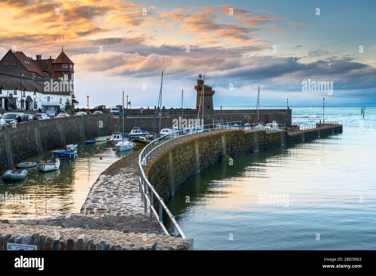 Come il sole che va giù i lampioni sfarfallio su attorno alla pittoresca North Devon porto di Lynmouth. Foto Stock