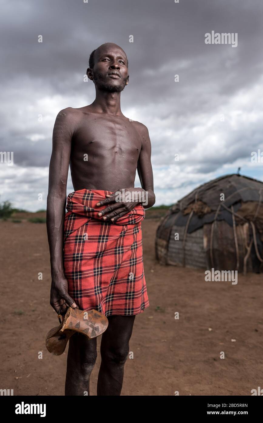 Un membro maschio del gruppo etnico o della tribù di Dassanetch pone di tenere la sua sedia intagliata a mano, Omorate, Etiopia meridionale. Foto Stock