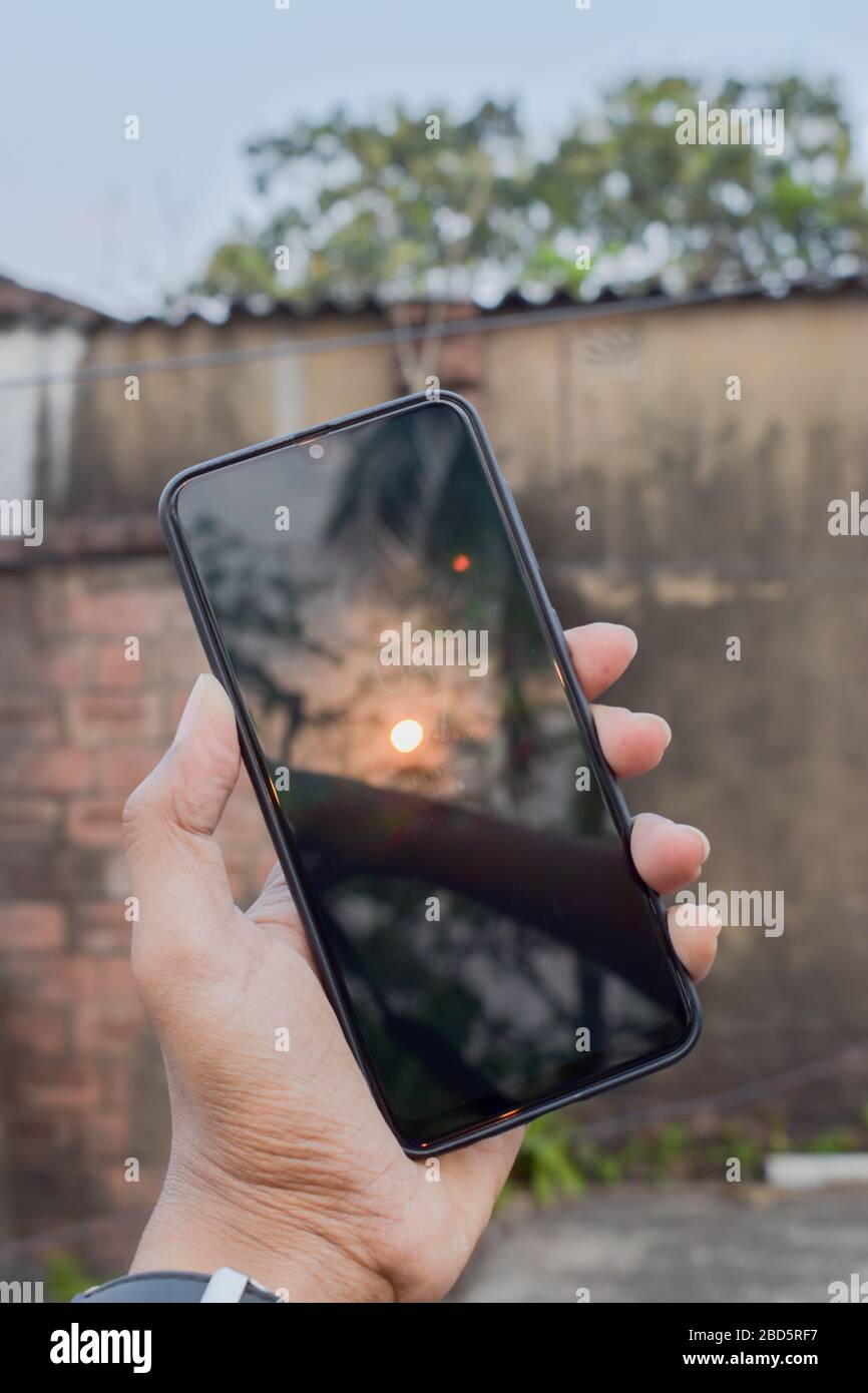 Catturare il tramonto sul telefono cellulare. Schermo del dispositivo smartphone con luce solare al tramonto. Temi fotografici. Background tecnologici. Foto Stock