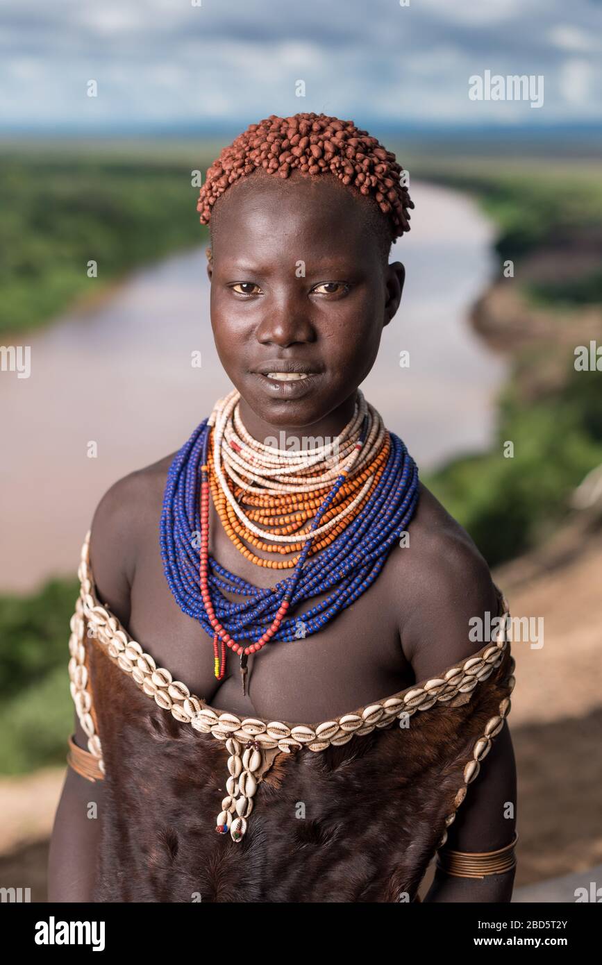 Sopra il fiume Omo, una tribù di Karo o membro del gruppo etnico indossa i suoi migliori perline e abito di pelle di capra, i suoi capelli intrecciati con argilla, Tumi, Etiopia. Foto Stock