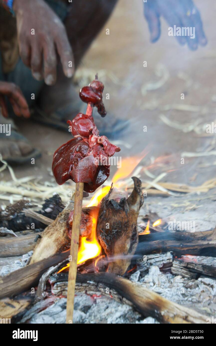 La carne animale cacciata viene cotta a fuoco aperto in un villaggio di Hadzabe. Fotografato al lago Eyasi, Tanzania Foto Stock