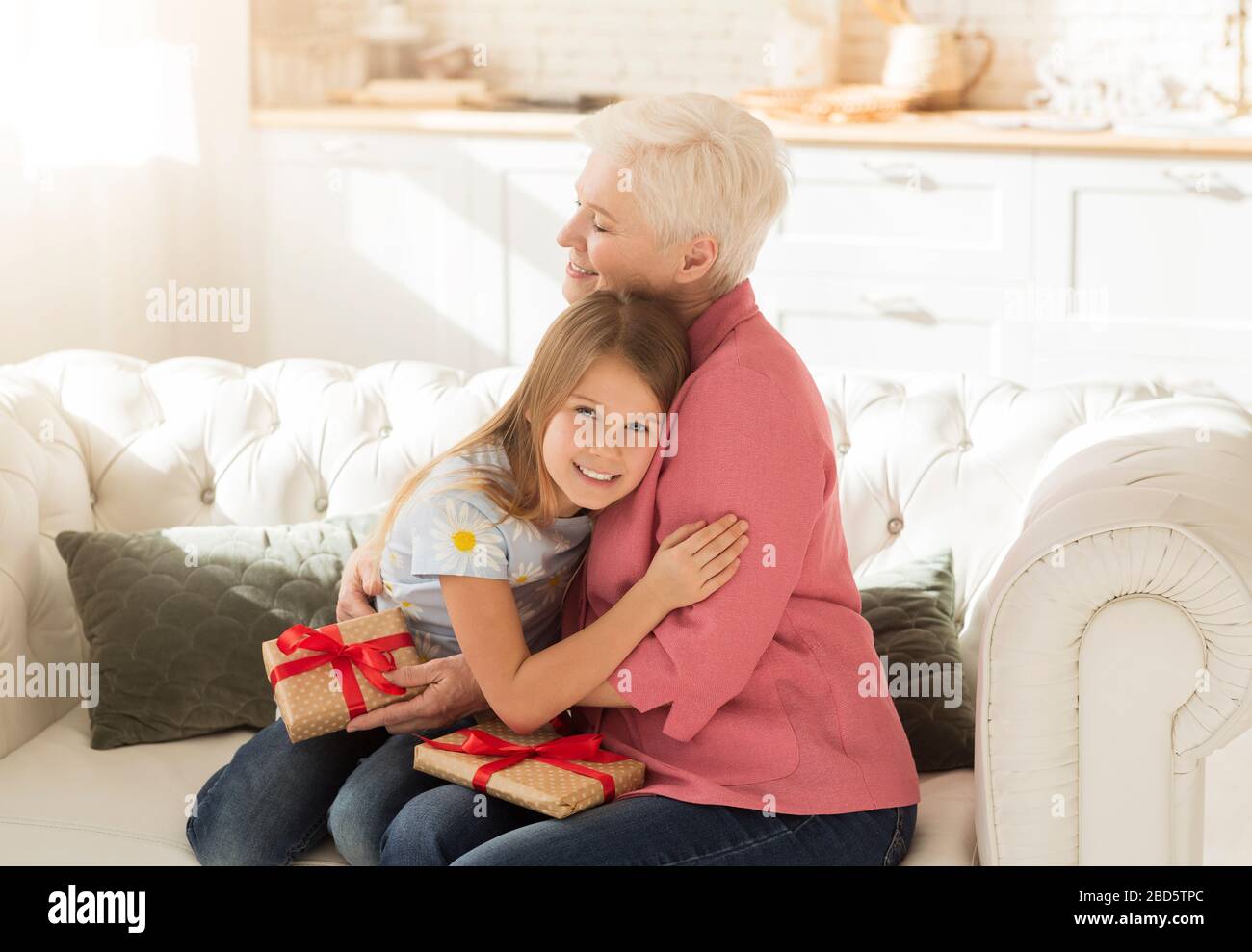 Grazie con i regali che abbracciano il suo nipote in soggiorno Foto Stock