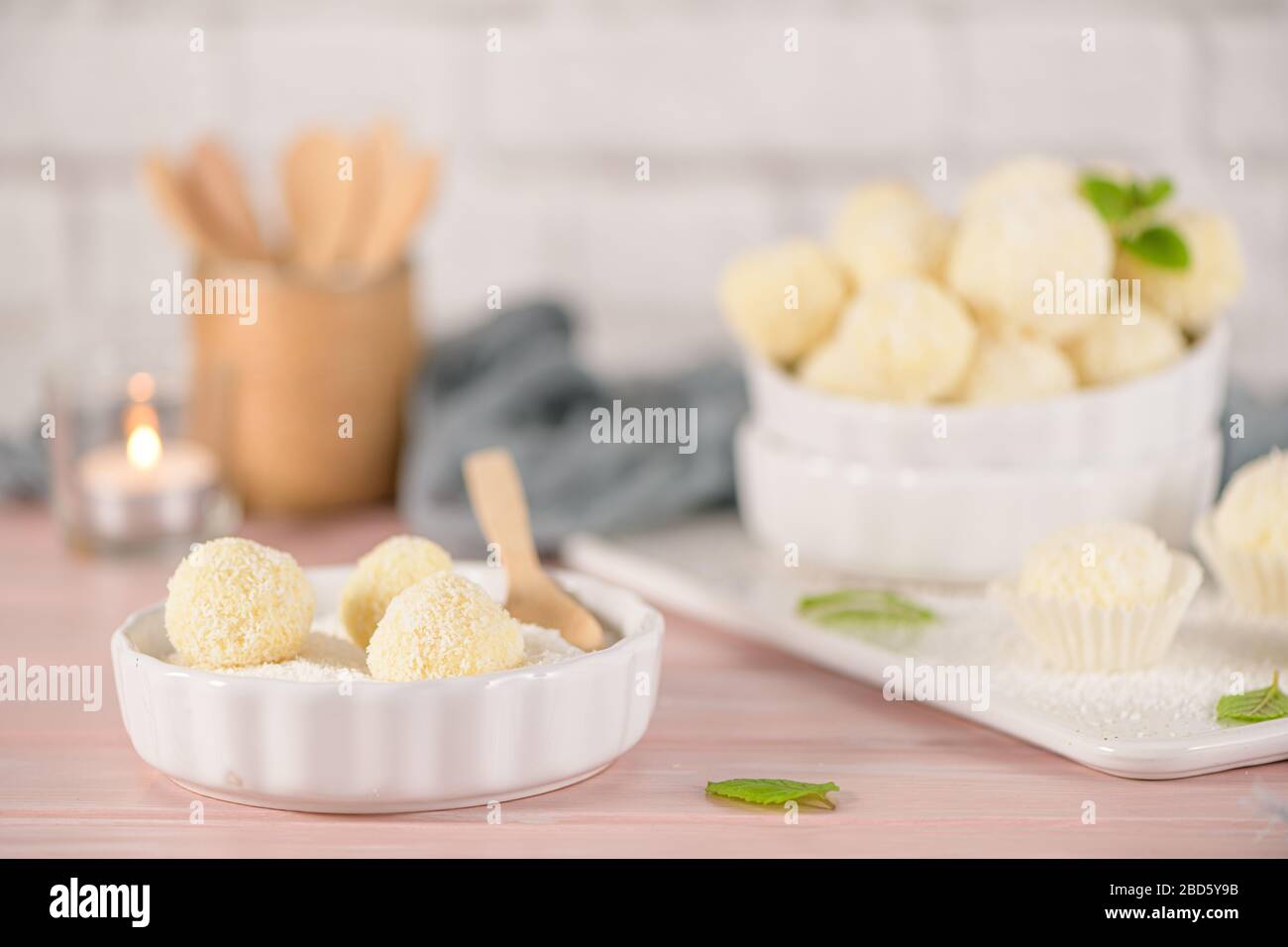 Caramelle fatte in casa con mandorle arrosto al cocco su un tavolo di legno rosa. Foto Stock