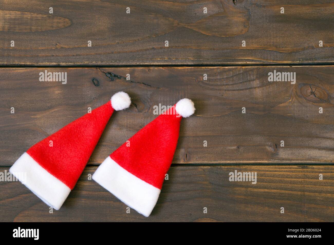 Idea della carta di Natale, due piccoli cappelli di santa su uno sfondo di legno con spazio di copia Foto Stock