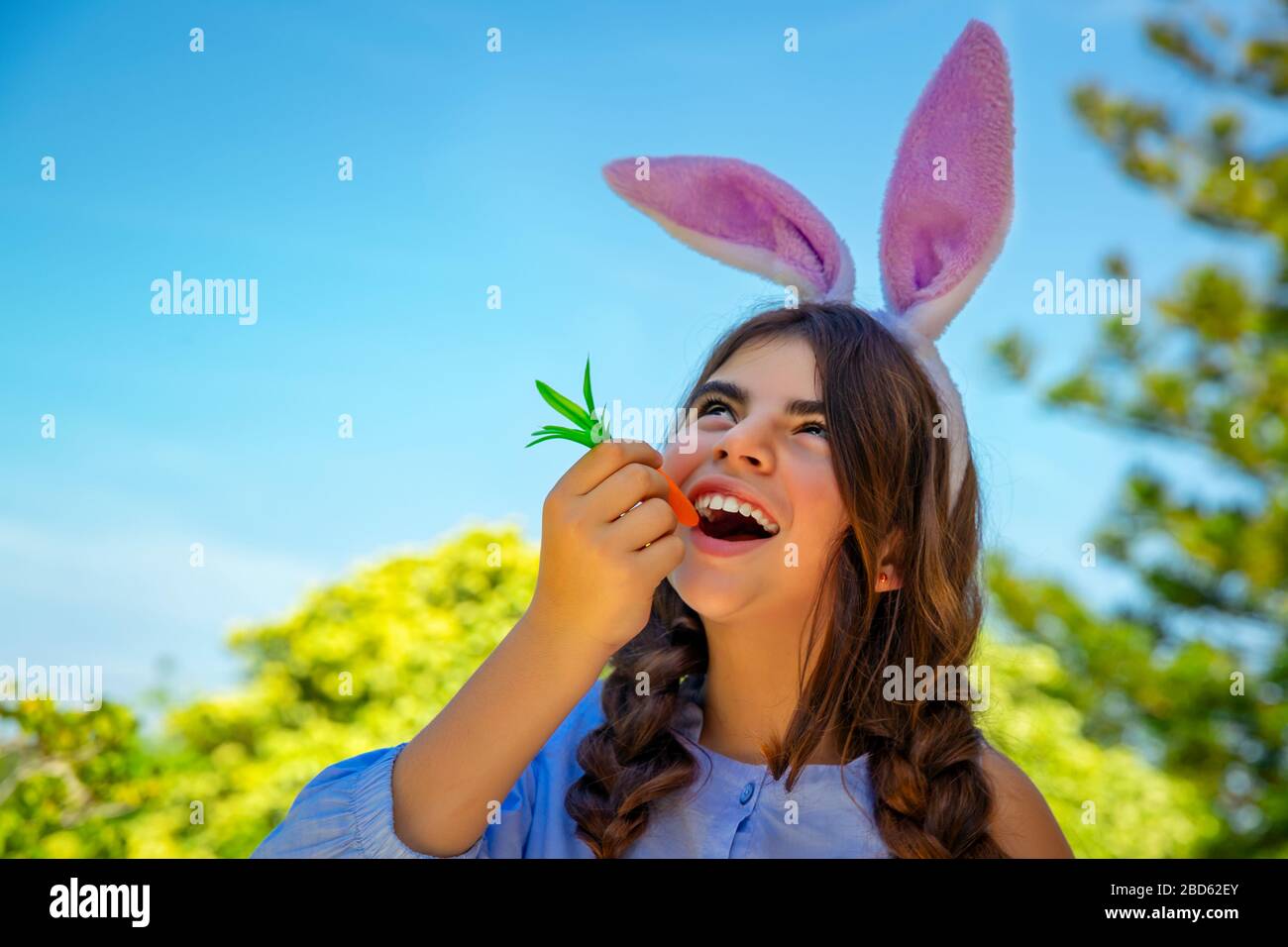 Ritratto di una bambina carina vestita da coniglietto con piacere mangiare  carota, simbolo tradizionale di Pasqua, felice primavera tempo all'aperto, costume  per bambini Foto stock - Alamy
