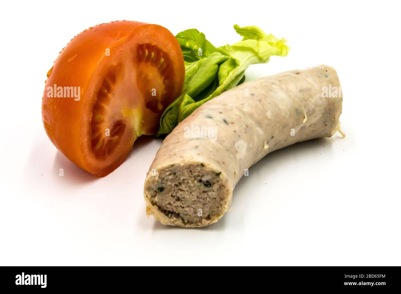 Un pezzo di salsiccia bianca su fondo bianco con mezzo pomodoro e una foglia di insalata Foto Stock